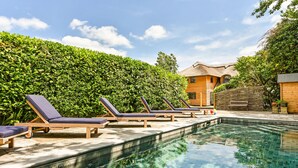 Une piscine avec des chaises longues et un bâtiment en bois en arrière-plan.
