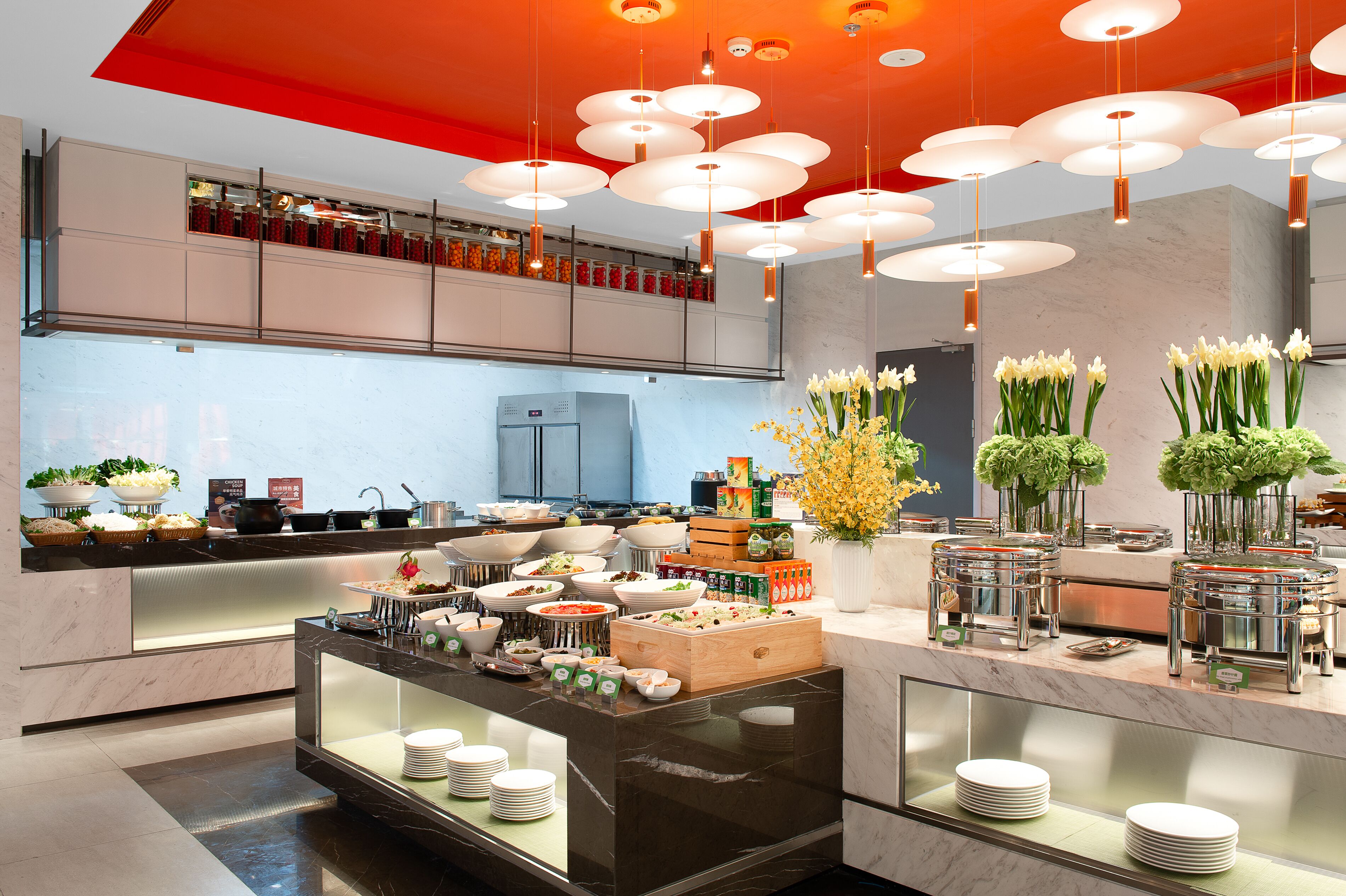 A modern kitchen with marble countertops, a built-in oven, and a variety of food items displayed on the counter.