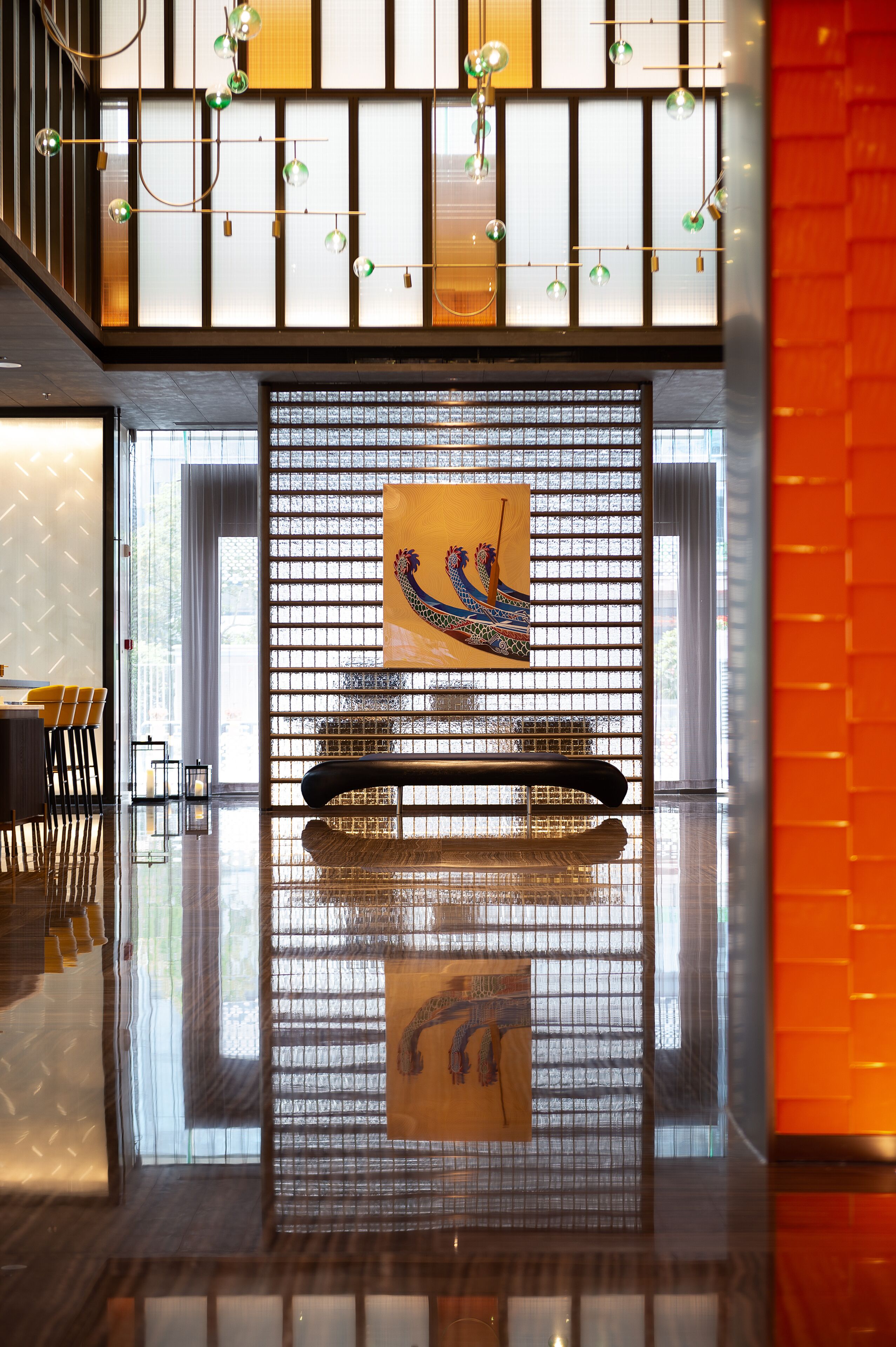 A modern interior with a reflective floor, a decorative wall with a geometric pattern, and a framed artwork of a peacock.
