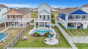 A residential area with houses featuring balconies, a swimming pool, and a fire pit area. - BRAND NEW 4/3.5 w/ heated pool and water views. Kid friendly and close to golf (Galveston)