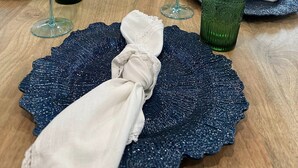 Une table à manger dressée avec de la verrerie verte, une serviette blanche et une assiette décorative.