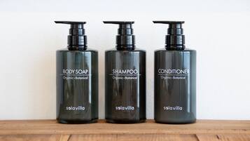 Three black bottles of Solavilla body products on a wooden surface.