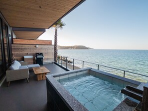 Una terraza moderna al aire libre con piscina, zona de estar y vistas al mar.