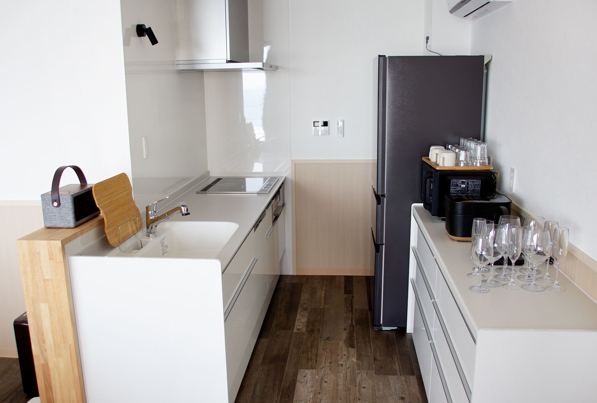 Una cocina moderna con encimera blanca, refrigerador negro y cafetera.