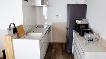 A modern kitchen with a white countertop, a black refrigerator, and a coffee machine.
