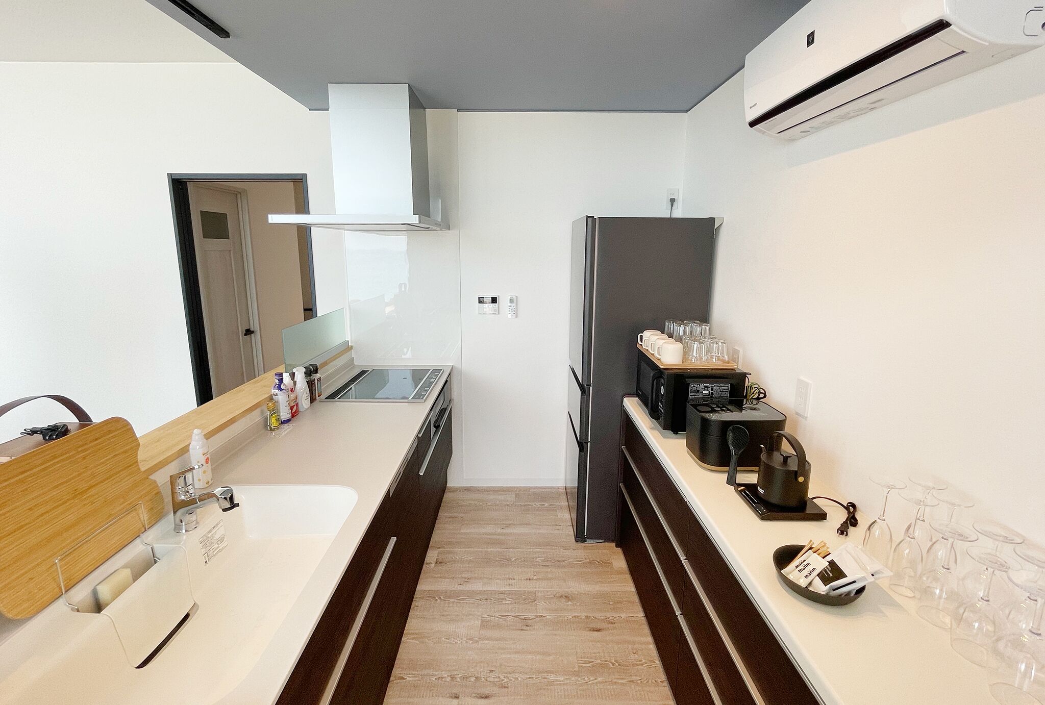A modern kitchen with a white countertop, stainless steel appliances, and a wooden floor.