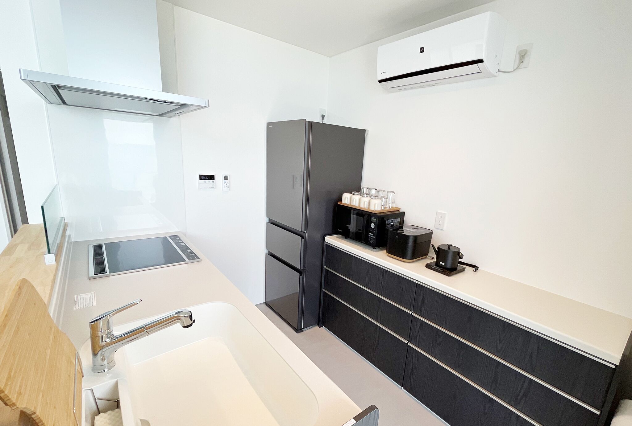 A modern kitchen with a stainless steel refrigerator, a coffee maker, and a microwave on the countertop.