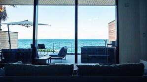 A room with a large sliding glass door leading to a balcony with a view of the sea. There are two chairs and a table on the balcony. - Solavilla Umi Terrace Minamiawaji (Minamiawaji)