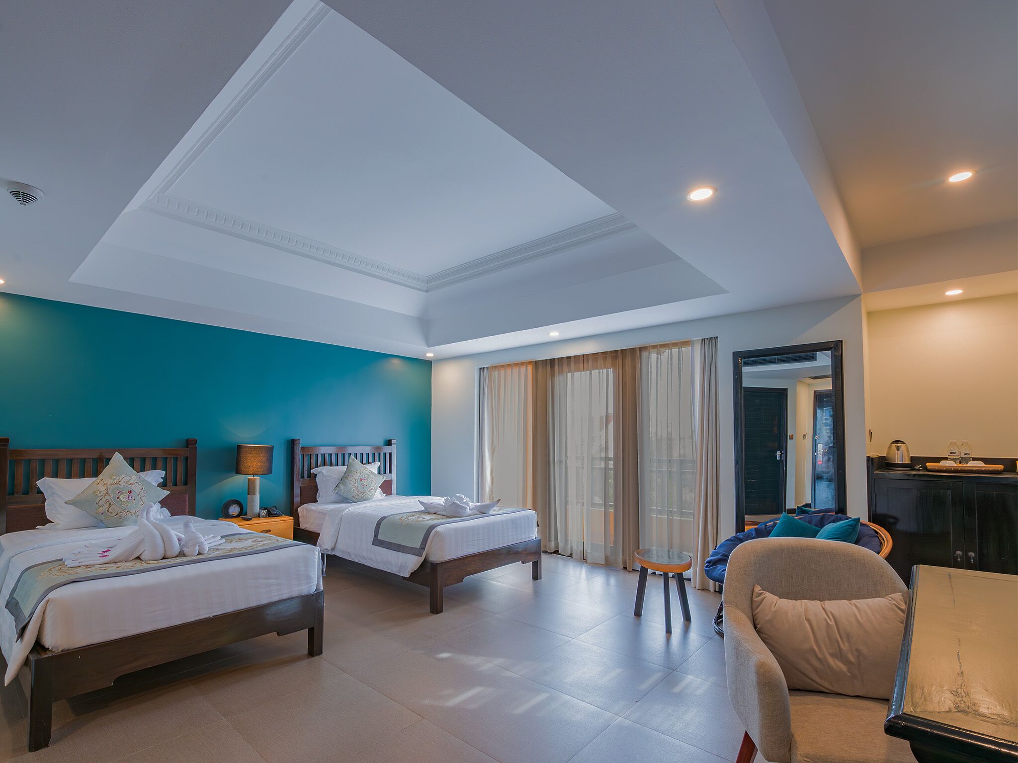 A hotel room with two beds, a sofa, a small table, and a mirror.