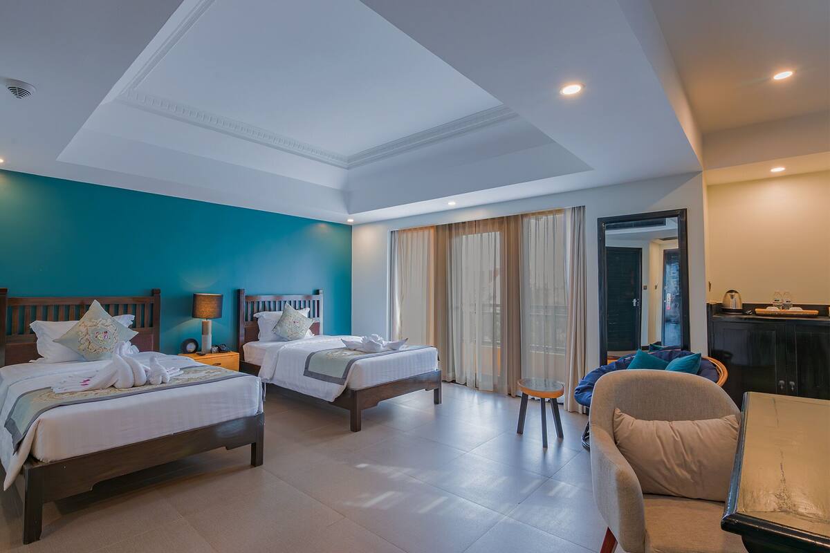 Una habitación de hotel con dos camas, un sofá, una mesita y un espejo.