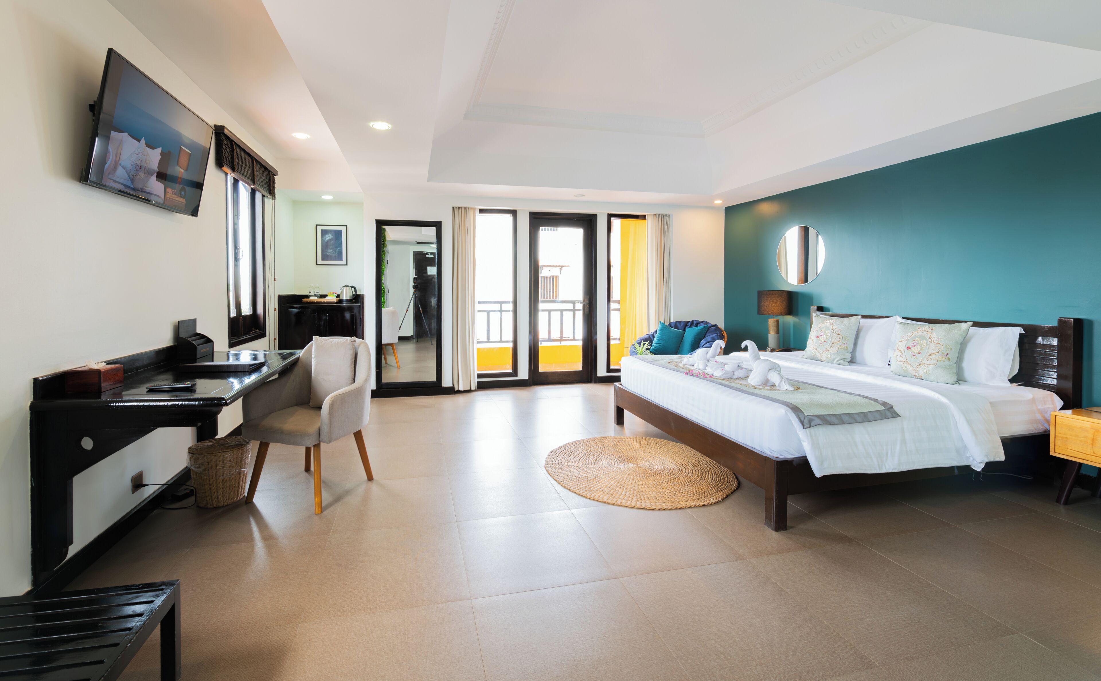 A hotel room with a bed, desk, chair, and a view through the door.