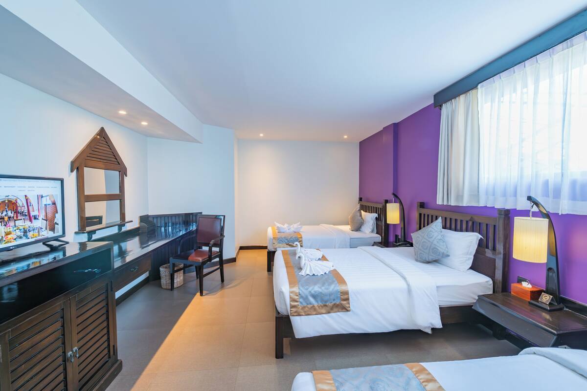 Habitación de hotel con dos camas, un escritorio, una silla y un televisor.