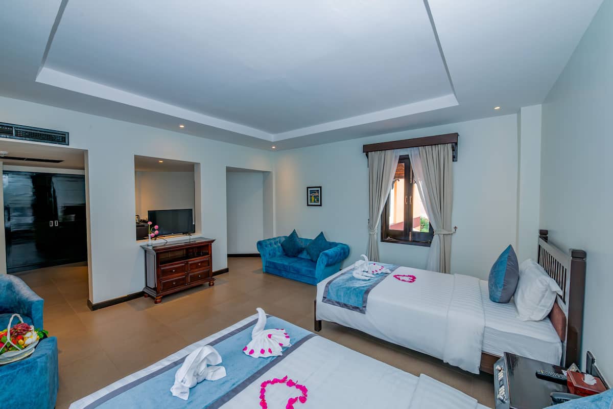 Ett hotellrum med två sängar, en TV, en soffa och en matplats.