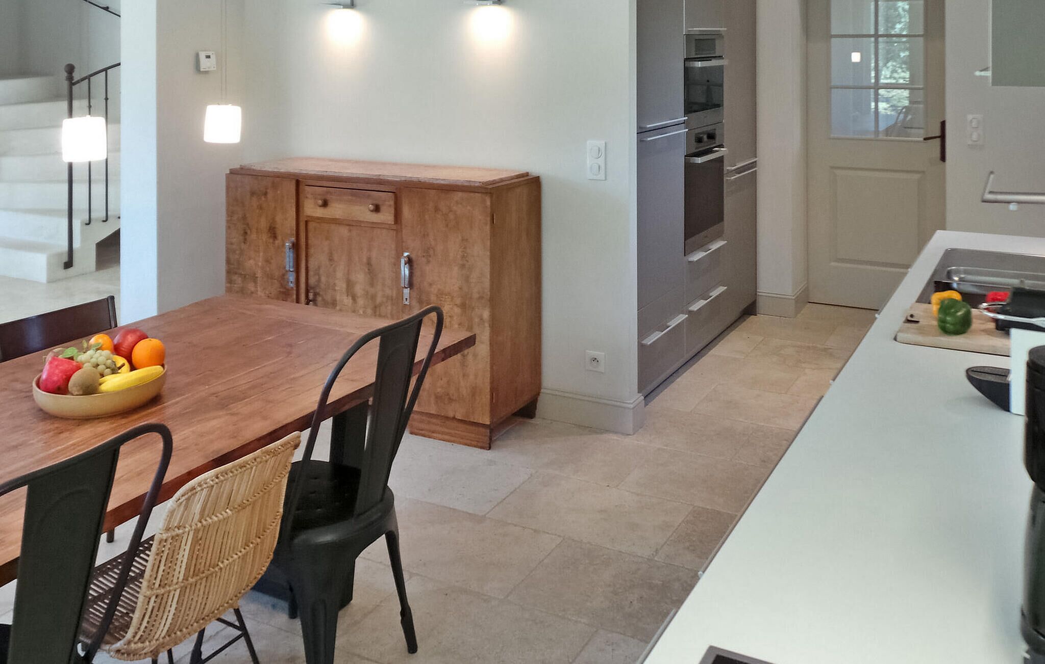 Een moderne keuken met een houten eettafel, twee stoelen en een fruitschaal.