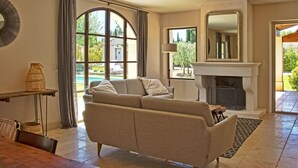Una sala de estar con sofá, chimenea, un ventanal grande y una zona de comedor.