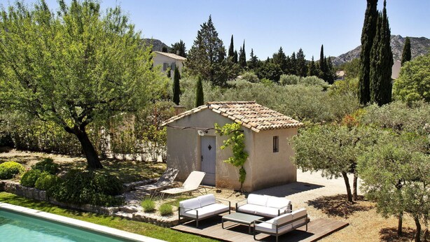 Una pequeña villa con piscina, mobiliario de exterior y jardín.