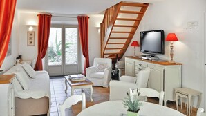 Een woonkamer met een bank, stoelen, een salontafel, een televisie en een trap.