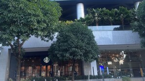 A modern building with a blue glass facade, a Starbucks entrance, and a bike parking area.