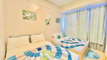A hotel room with two beds, each with a blue and white checkered blanket, a green towel, and a small painting on the wall.