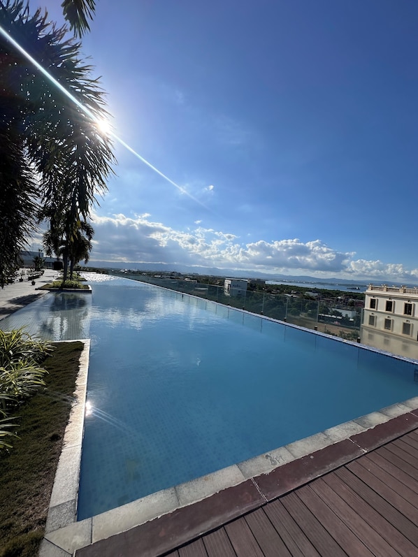 A clear blue sky, a swimming pool, and a view of distant buildings.