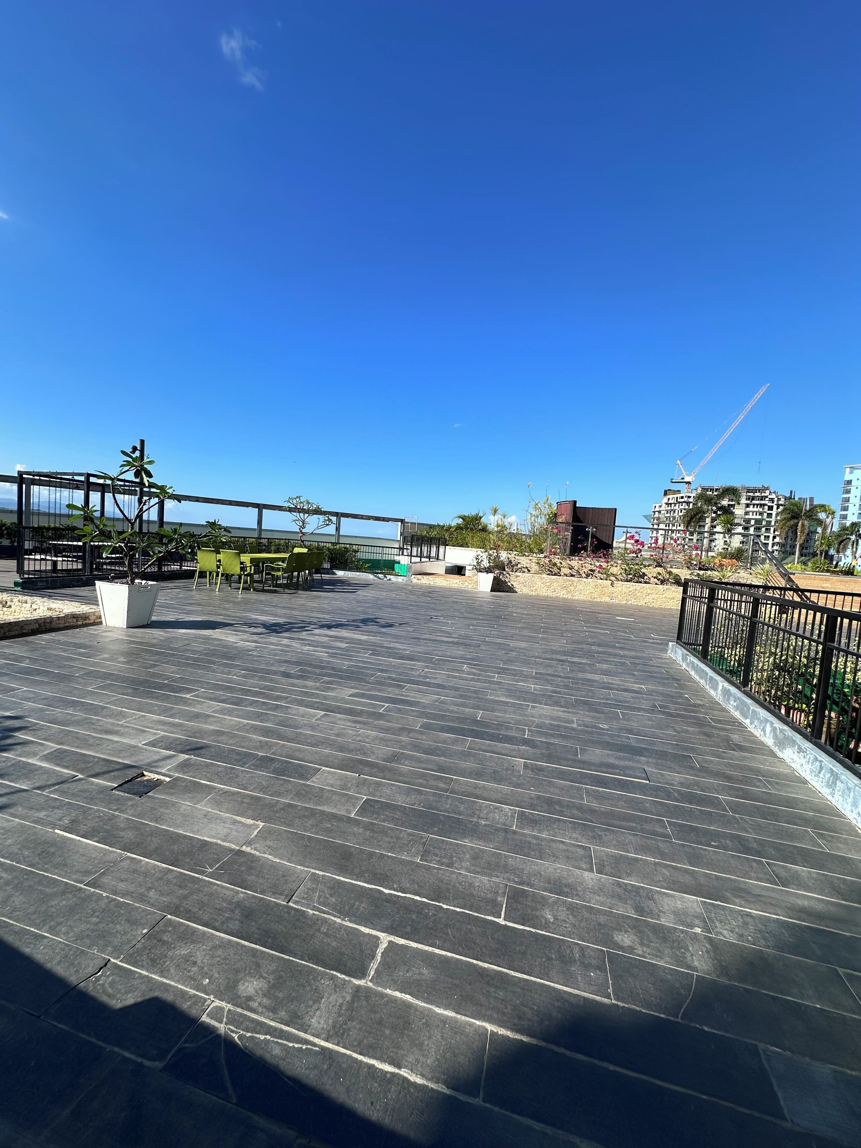 Terraza en la azotea con suelo de baldosas, baranda metálica y vista a una obra en construcción al fondo.