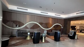 A modern lobby with a seating area, a reception desk, and a patterned wall.