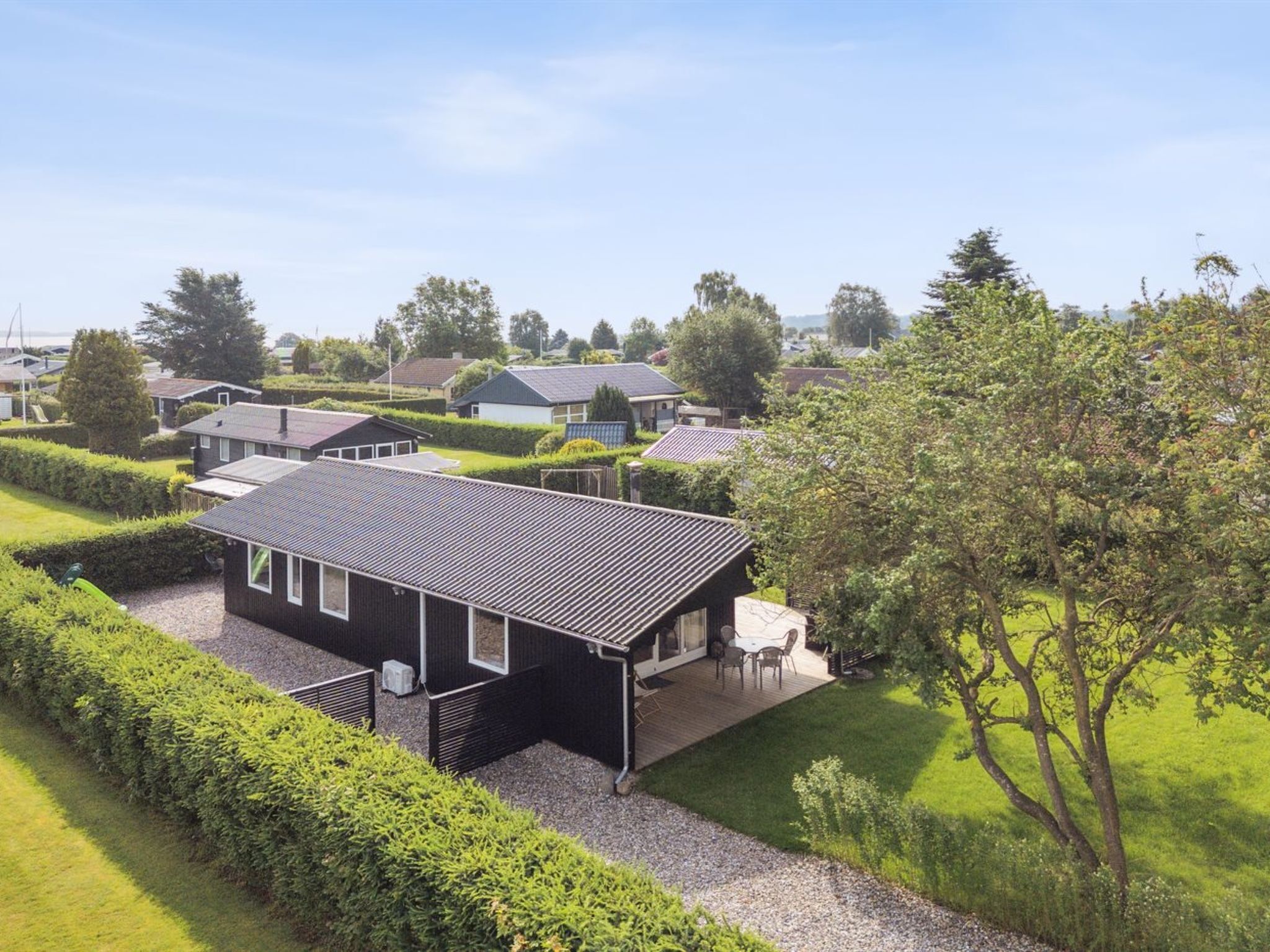 A modern house with a flat roof, a covered patio, and a well-maintained garden.