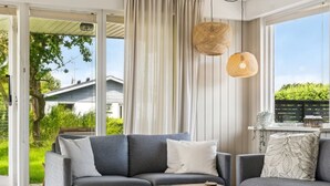 A modern living room with a grey sofa, a wooden coffee table, and a large window with curtains. - "Volmer" - 700m from the sea by Interhome (Hejls)