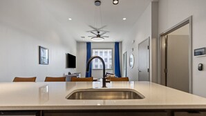 Una cocina moderna con una isla central, un ventilador de techo y vistas a la ciudad a través de amplios ventanales.