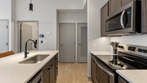 Una cocina moderna con un lavamanos de acero inoxidable, un microondas y una estufa.