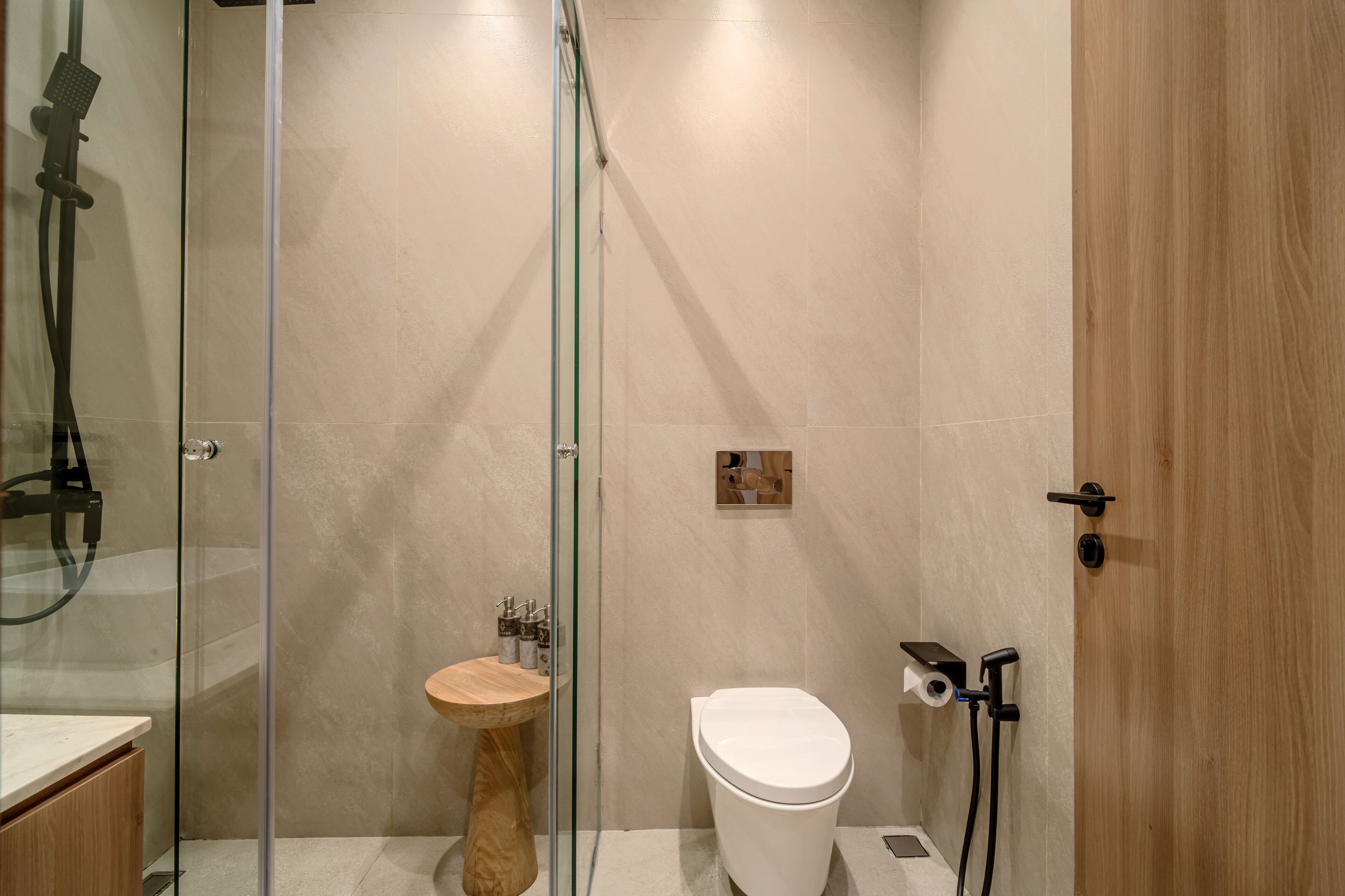 A modern bathroom with a glass-enclosed shower, a wooden vanity, and a toilet.