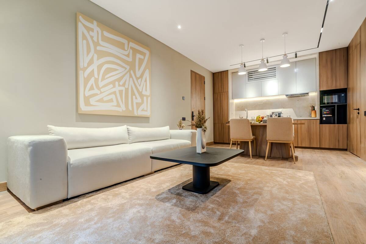 Una sala de estar moderna con un sofá blanco, una mesa de centro negra y un cuadro abstracto grande en la pared.