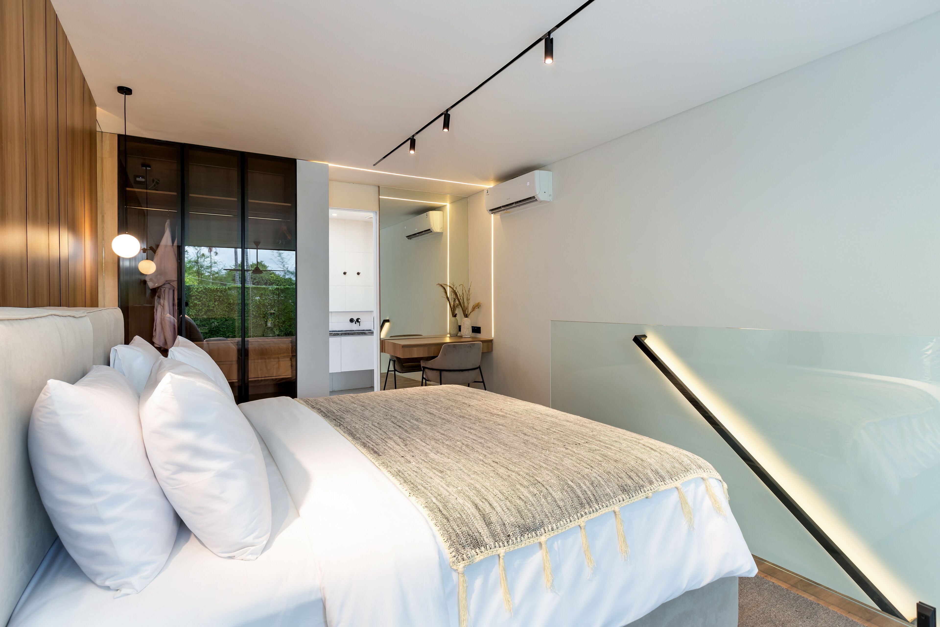 A modern bedroom with a bed, bedside table, and a desk area.