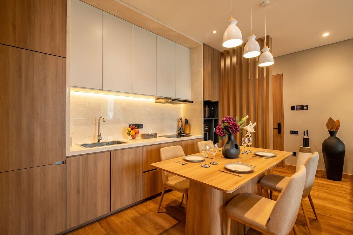 Una cocina moderna con armarios de madera, un lavamanos integrado e iluminación colgante.