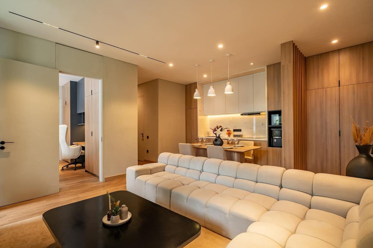 Una sala de estar moderna con un sofá, una mesa de centro y una cocina al fondo.
