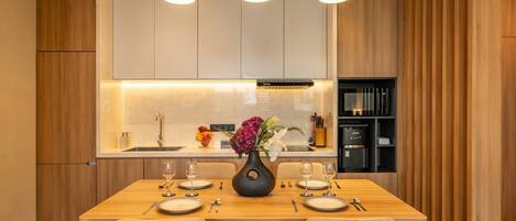 A modern kitchen with wooden cabinets, a central island with a vase of flowers, and pendant lighting.