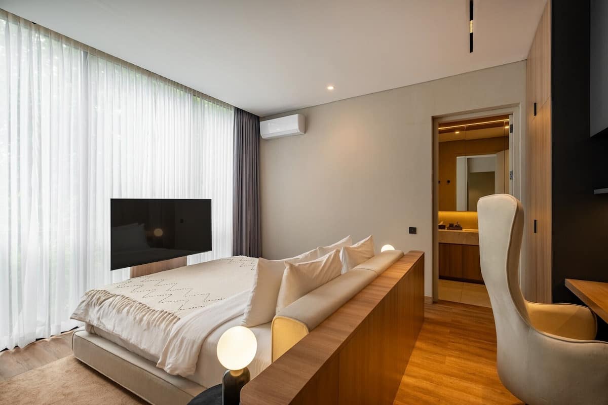 Una habitación de hotel moderna con una cama grande, televisión, zona de estar y kitchenette.