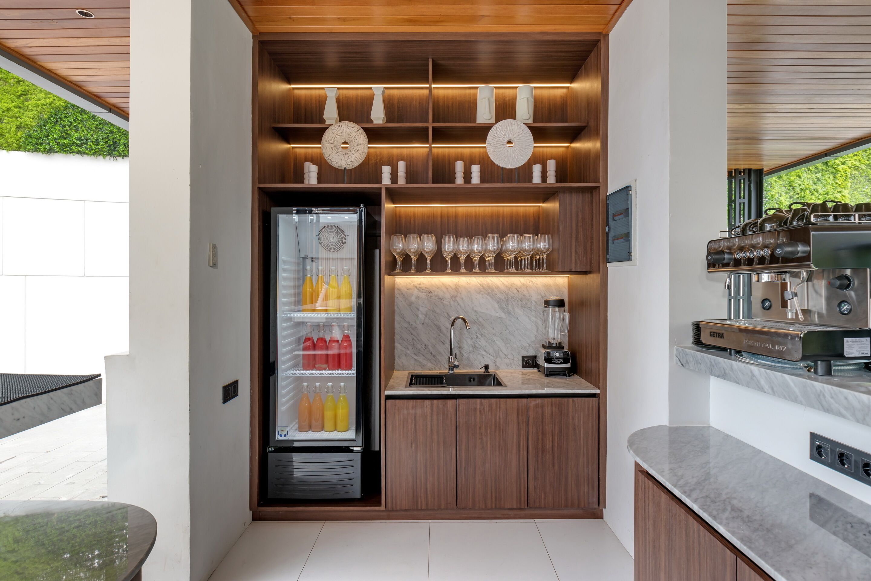 Una cocina compacta equipada con refrigerador, cafetera y un soporte para copas de vino.
