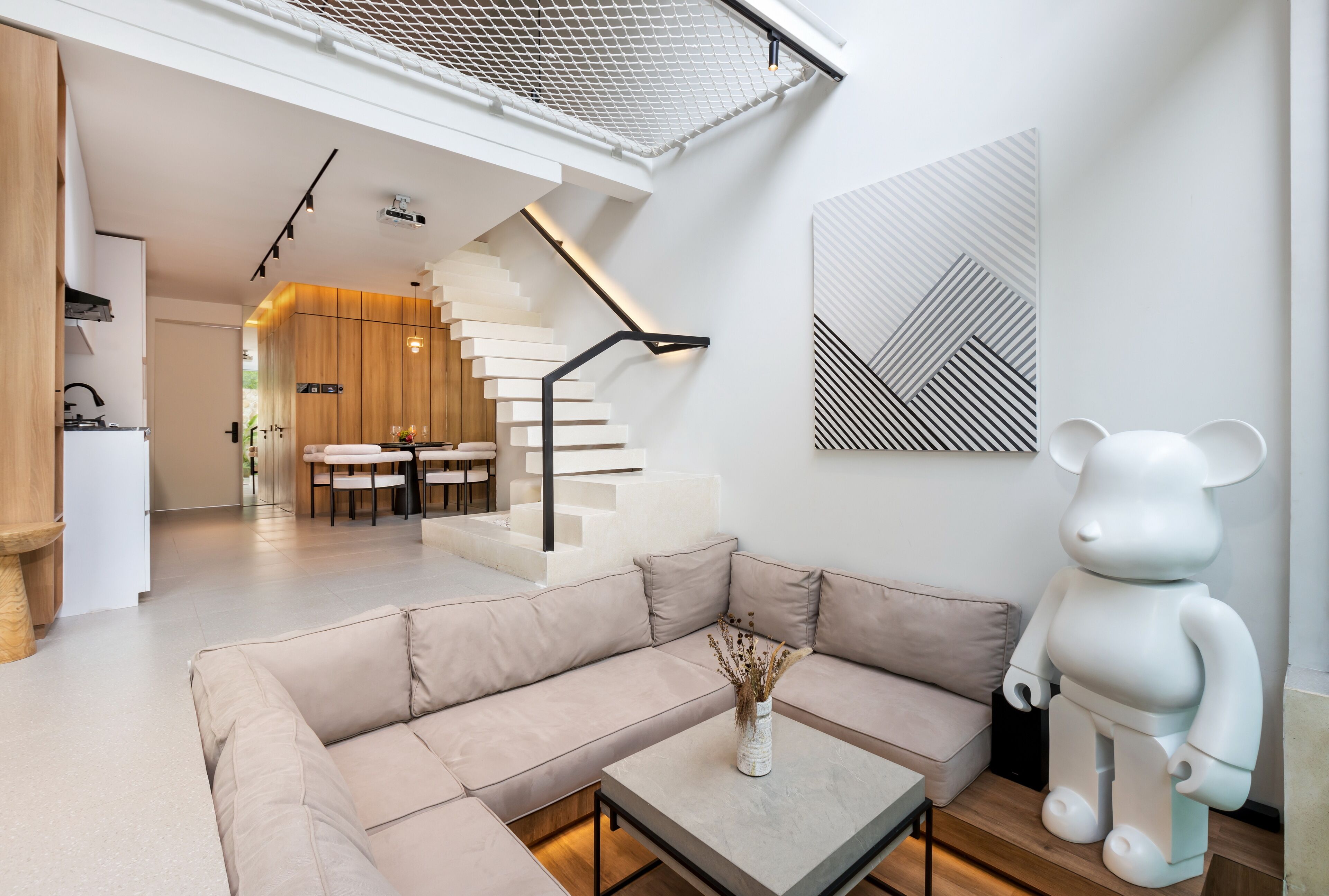 A modern living room with a beige sectional sofa, a coffee table, and a white bear sculpture.