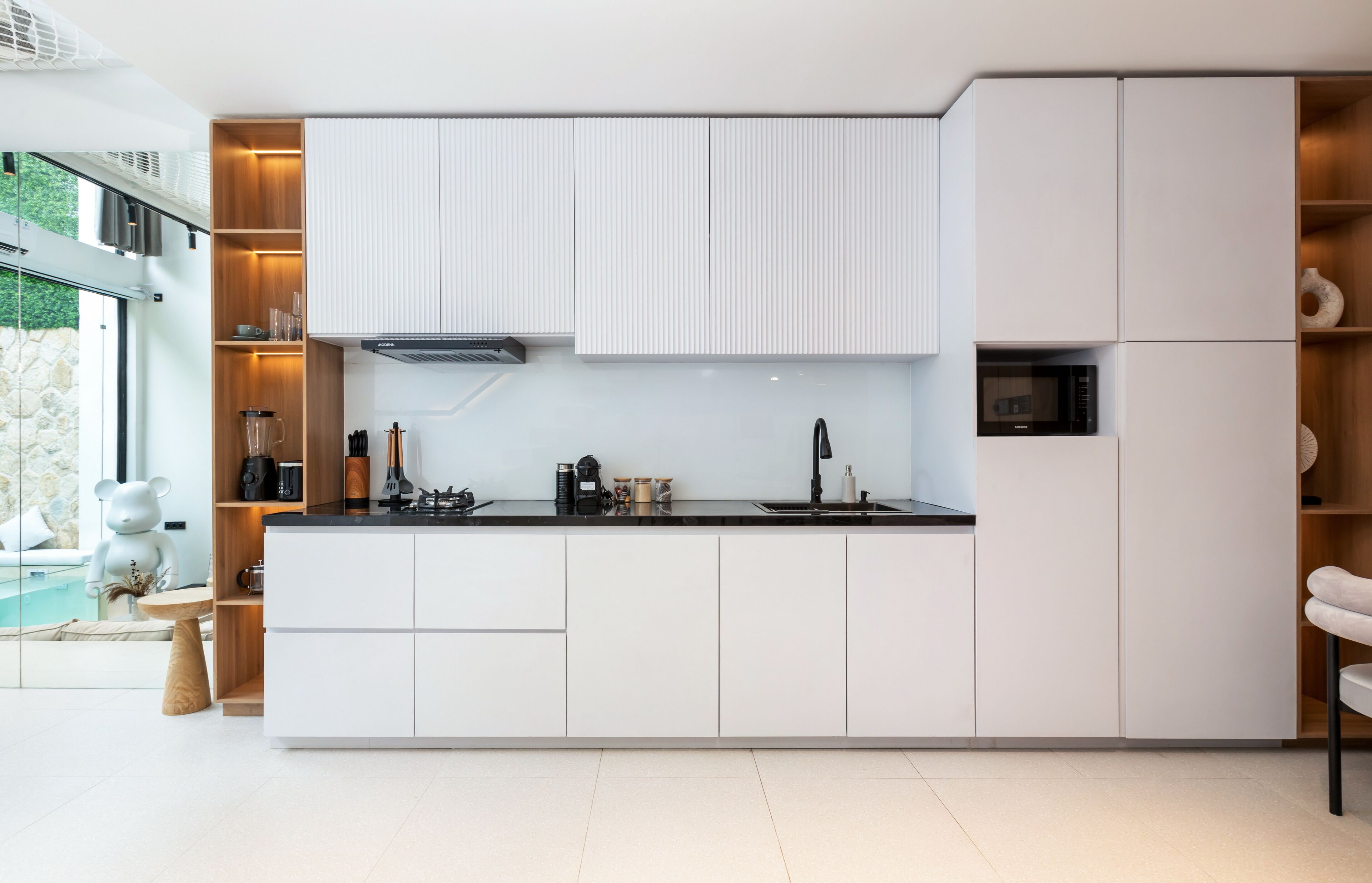 A modern kitchen with white cabinets, a black countertop, and a built-in microwave.