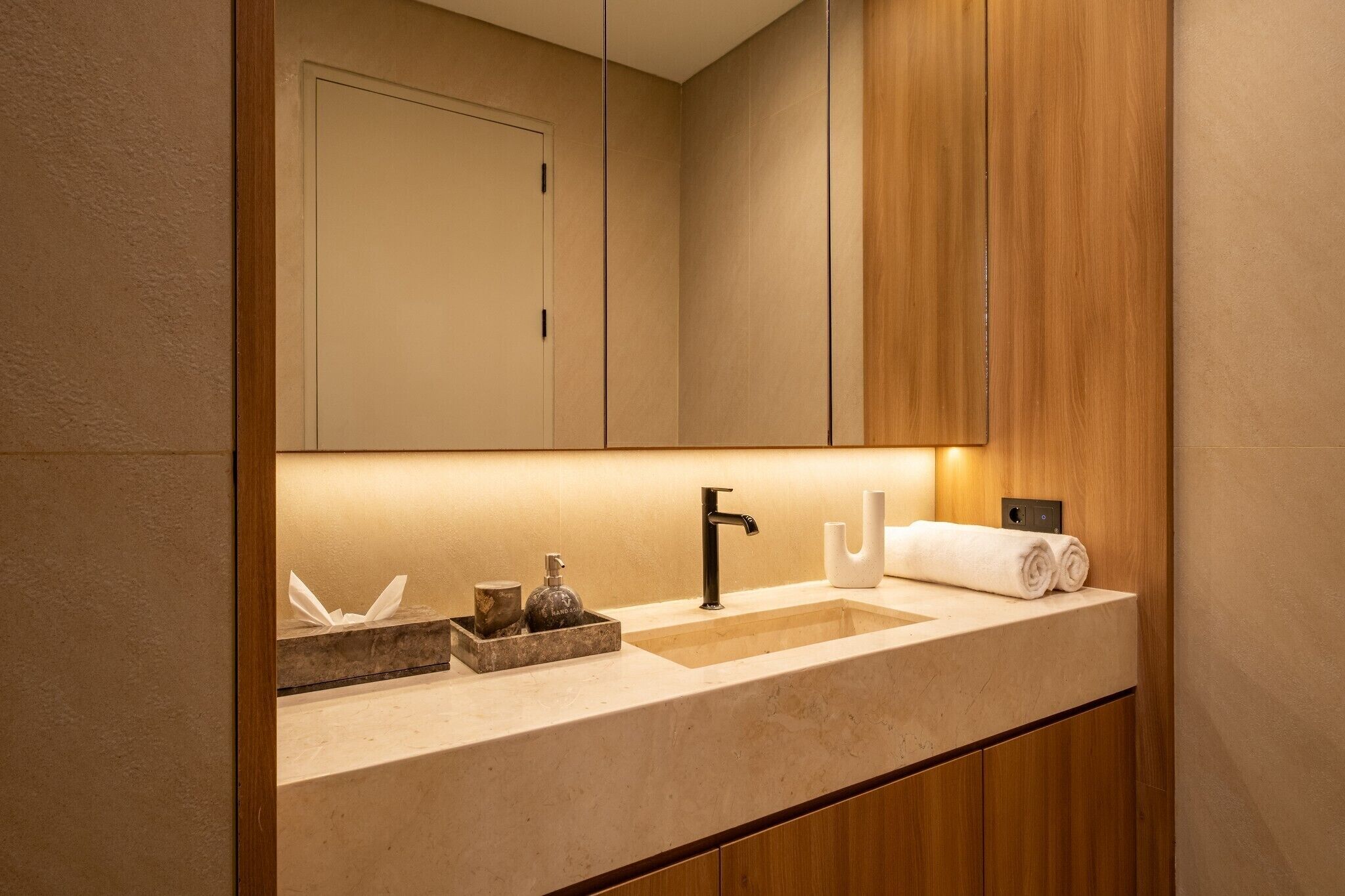Un baño moderno con un espejo grande, un lavabo y armarios de madera.
