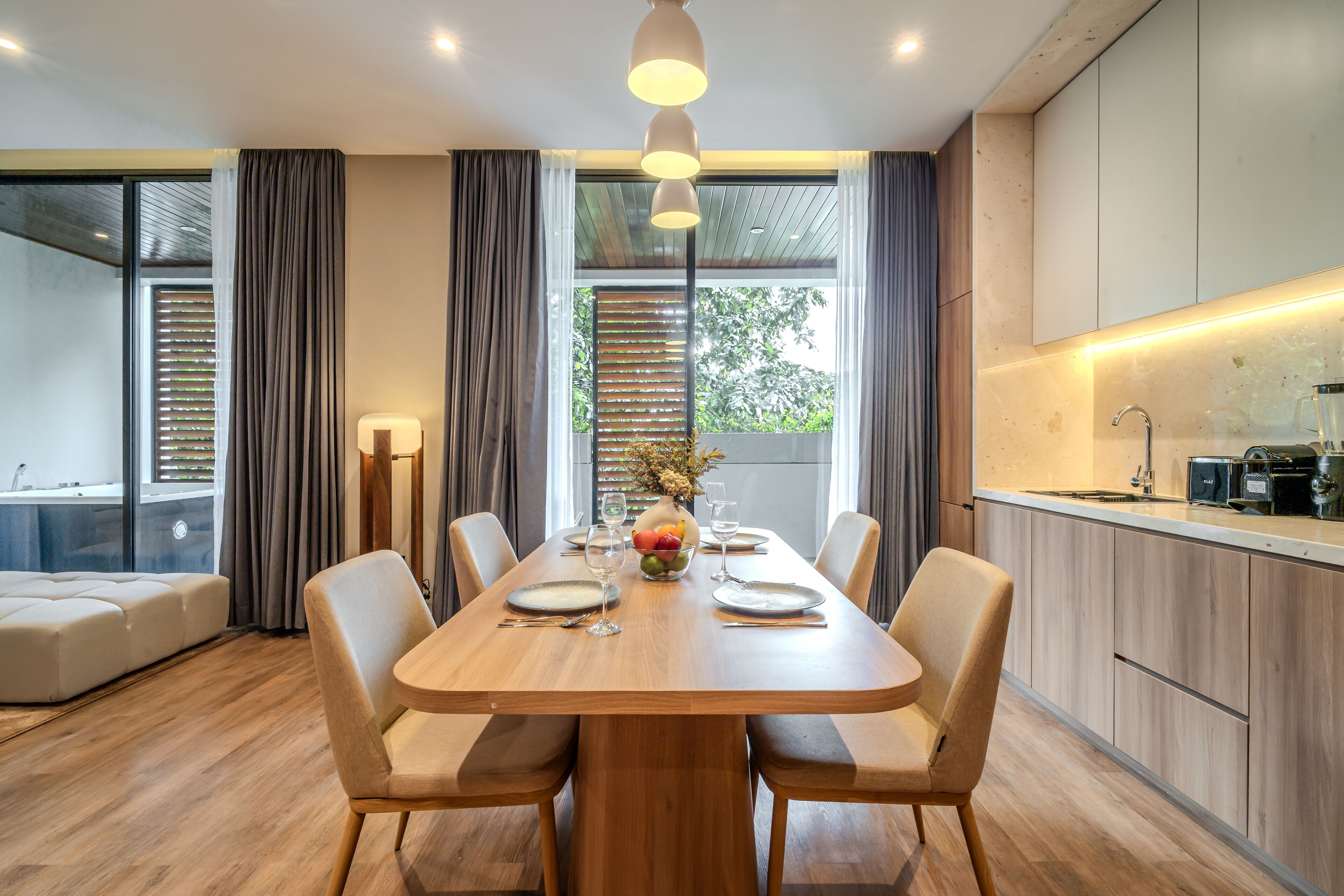 A modern dining area with a wooden table, six chairs, and a central fruit bowl.