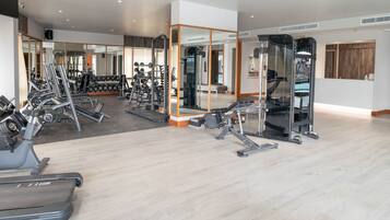 A modern gym with various exercise equipment, including treadmills, weight machines, and free weights.
