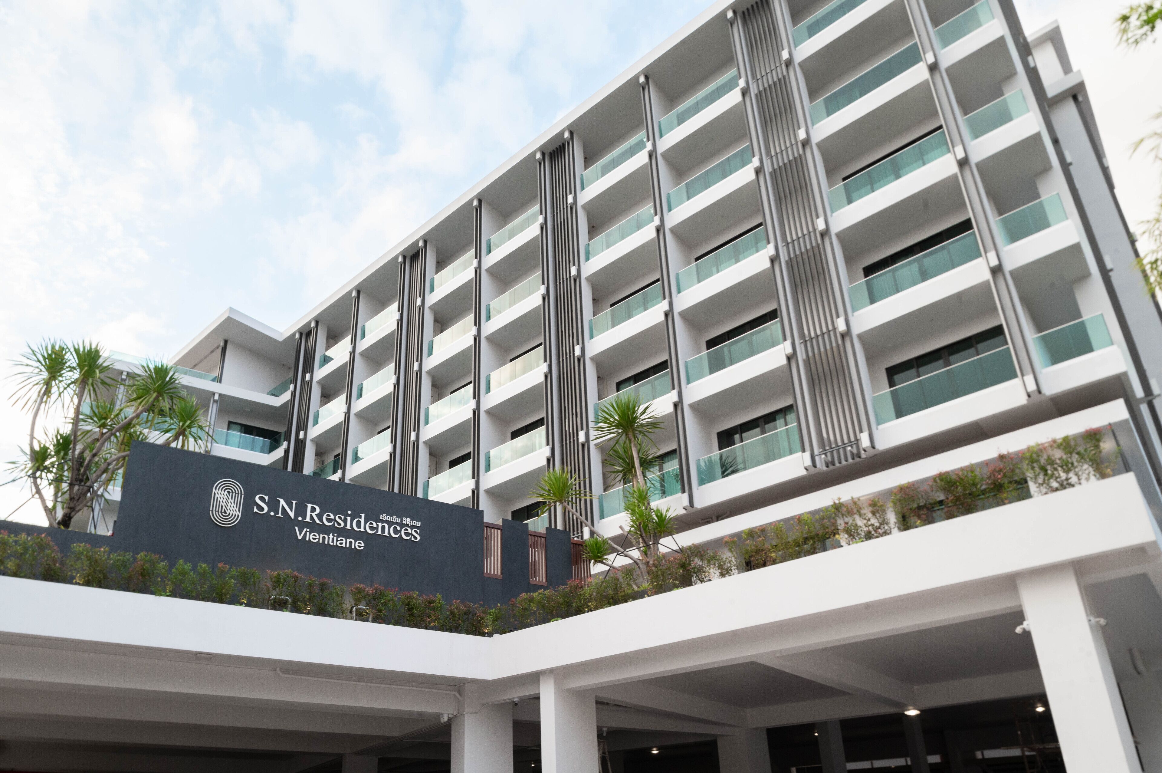 Un moderno edificio de hotel con varios balcones y un cartel que indica que es S.N. Residences Vientiane.