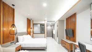 A modern hotel room with a bed, a desk, a chair, a TV, and a bathroom in the background. - SN Residences (Vientiane)