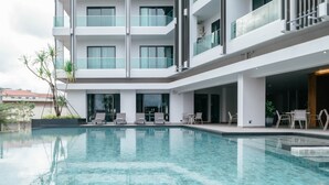 A modern hotel with a swimming pool, multiple balconies, and outdoor seating areas. - SN Residences (Vientiane)