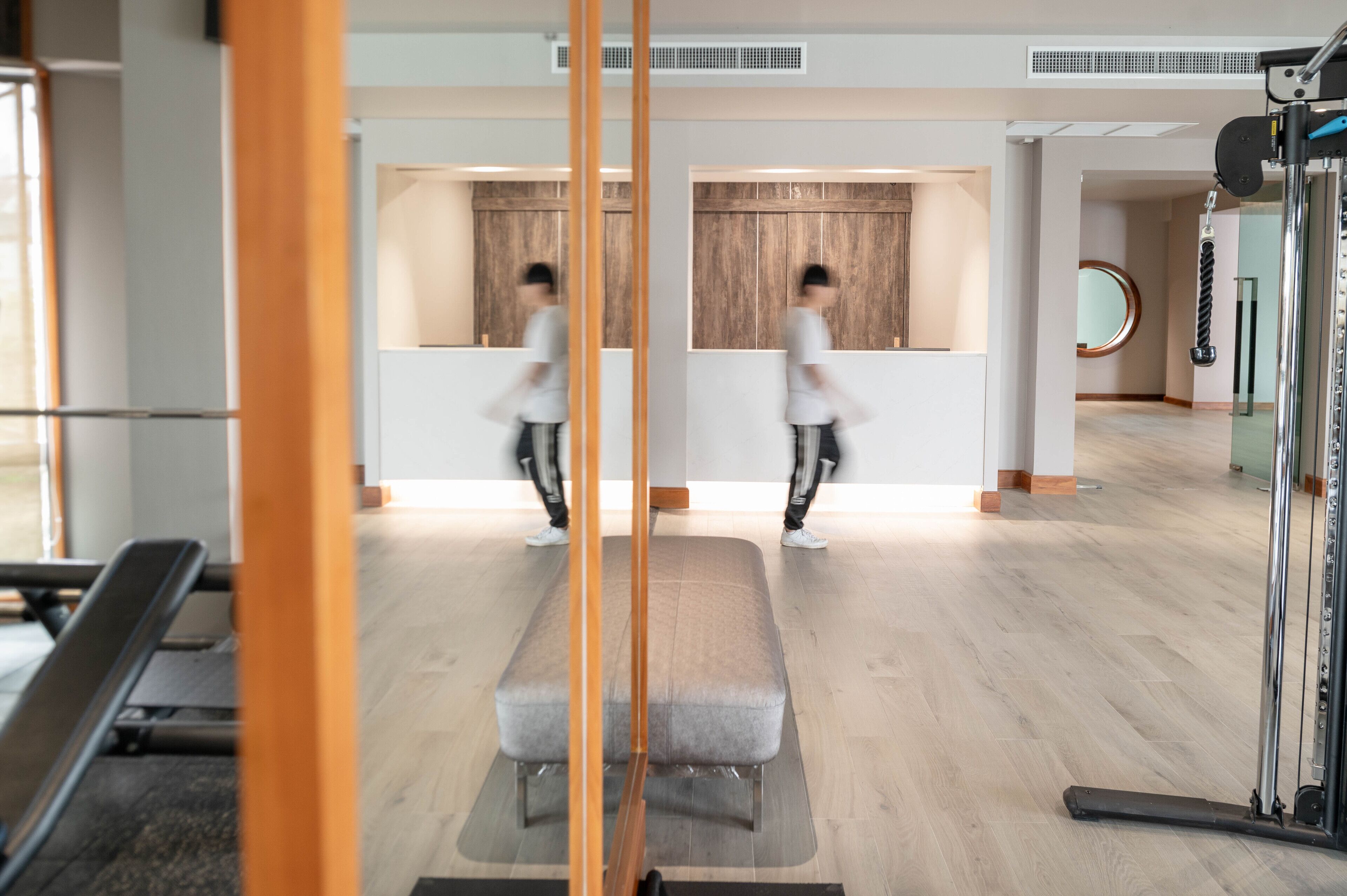 A gym with exercise equipment, a bench, and a mirror.