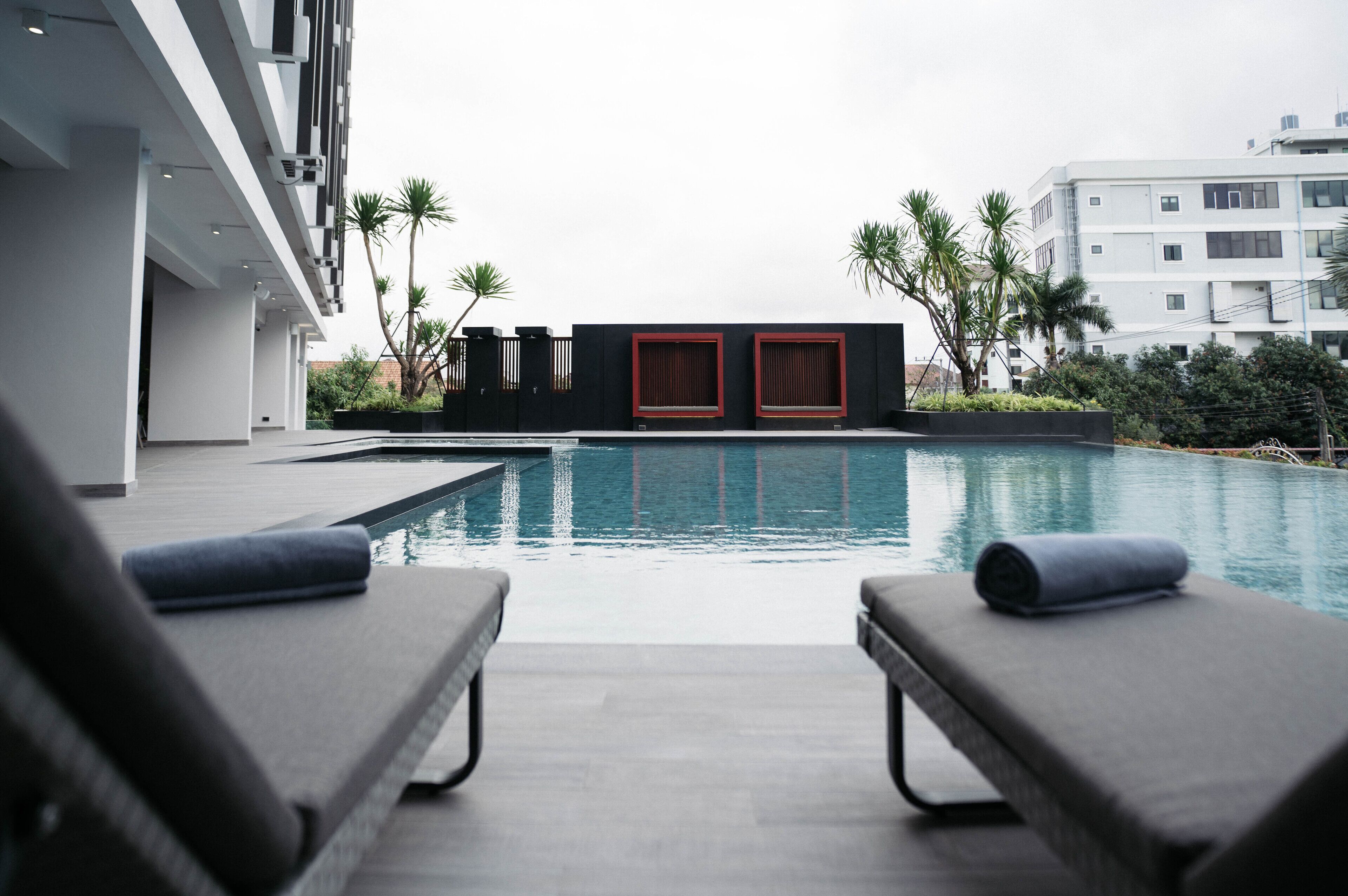 A modern hotel pool area with lounge chairs and a view of the pool.