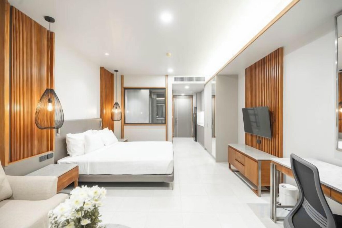 A modern hotel room with a large bed, a desk, and a television.