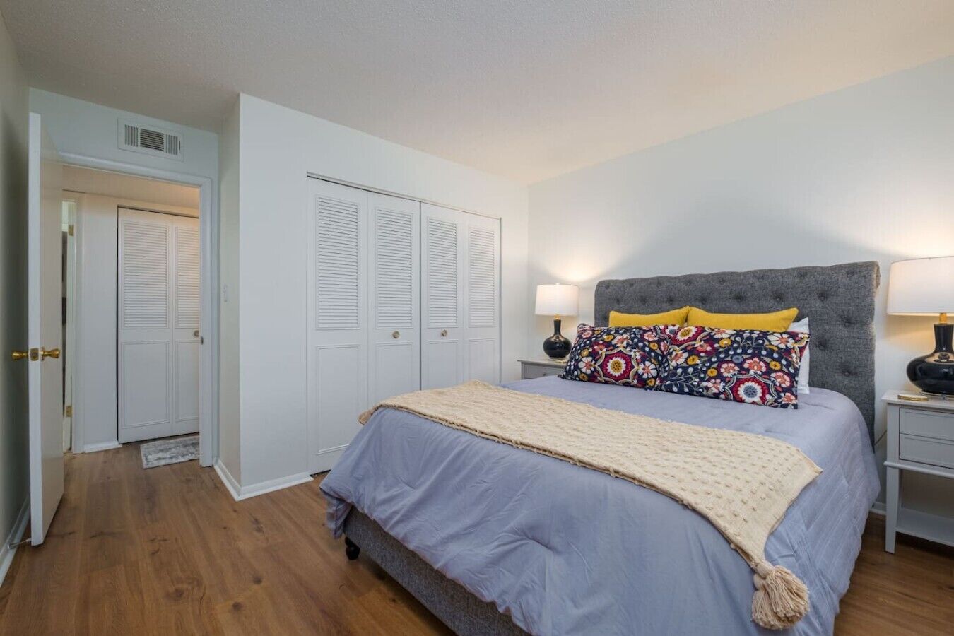 Ein Schlafzimmer mit einem Bett, zwei Nachttischen, einem Kopfteil, einem Kleiderschrank und einer Tür.